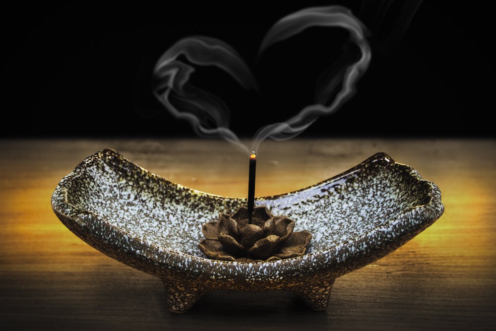 Candle in lotus holder with smoke making a heart shape